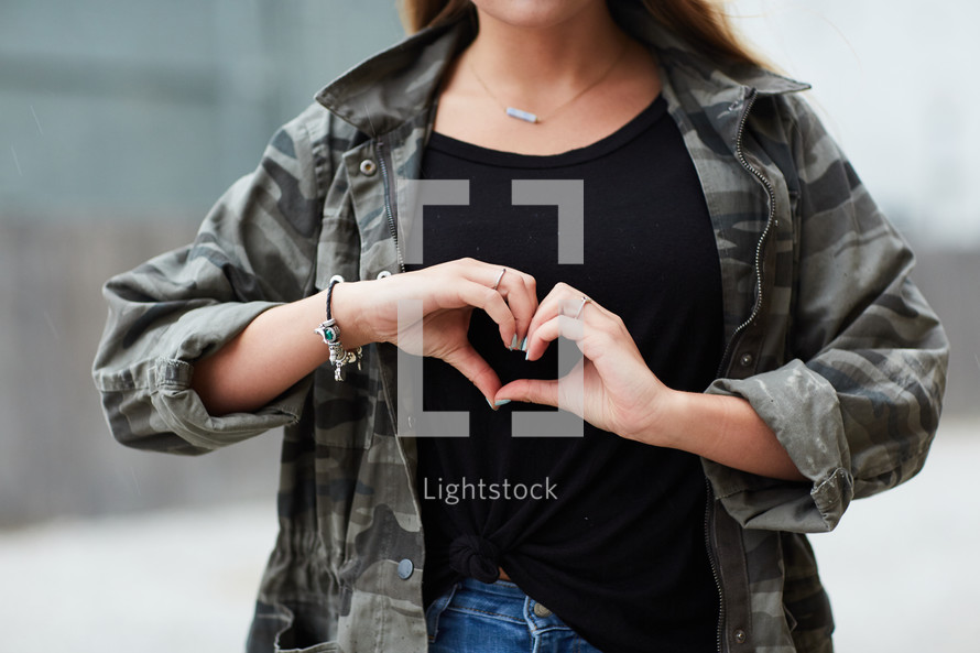 teen girl making a heart symbol with her hands 