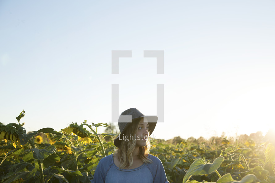 a woman standing in a field of sunflowers under a blue sky 