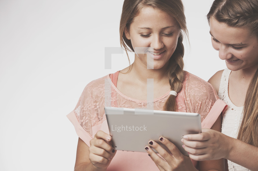 teen girls holding an iPad