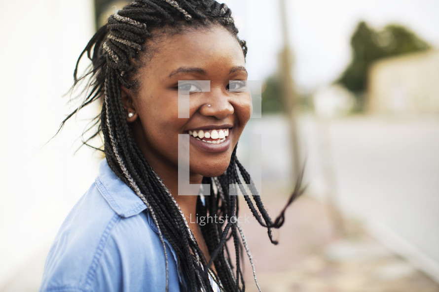 a smiling young African American woman with braids 
