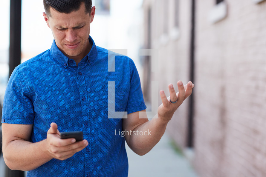 a frustrated man looking at a cellphone screen 
