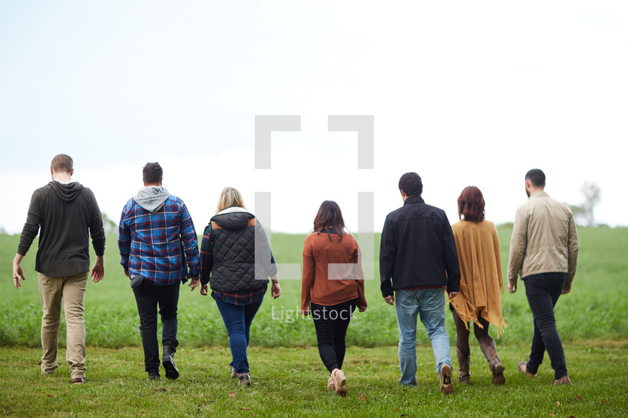group walking through a field of green grass in fall 