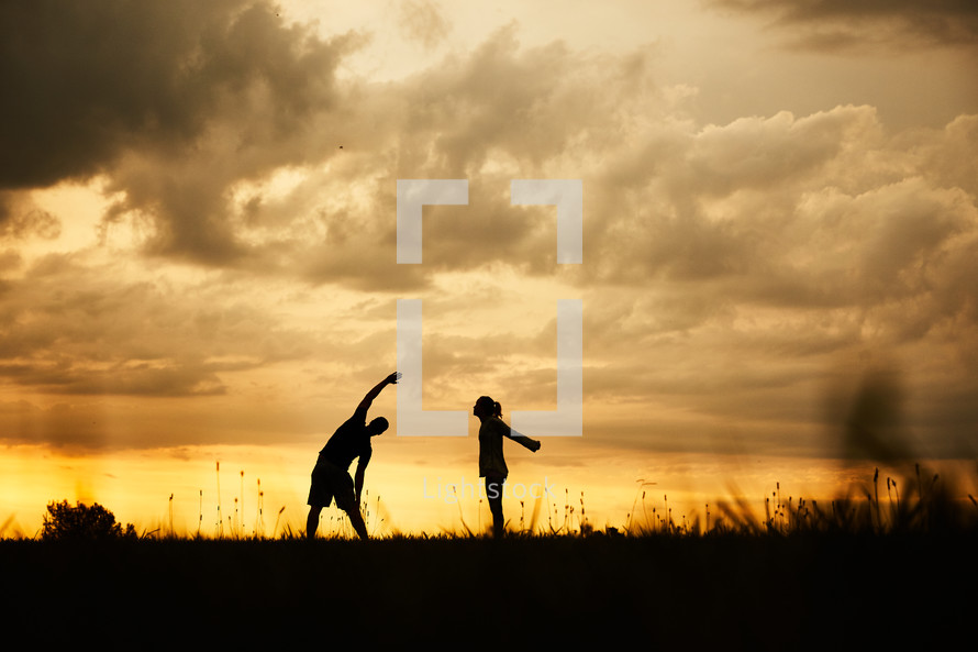 silhouettes of a couple stretching at sunset 