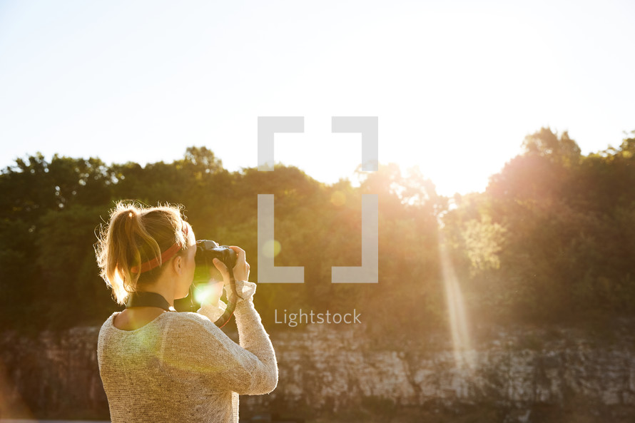 a woman taking a picture of the sunset with her camera 
