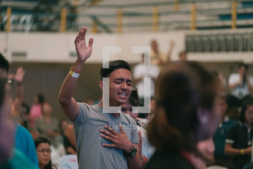 man with hand raised during a worship service 