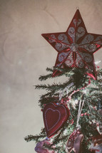A star ornament at the top of a Christmas tree 