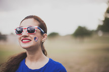 woman wearing stars and stripes sunglasses and a temporary tattoo 