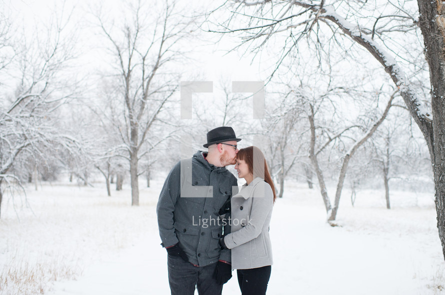 a couple kissing outdoors in the snow 