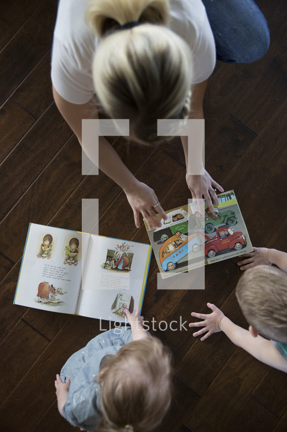 a mother reading a book to her son and daughter 