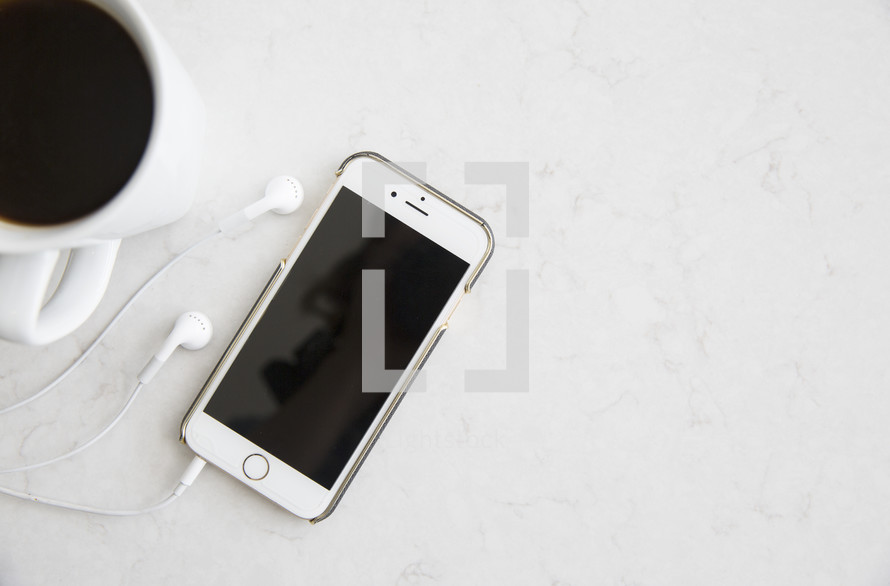coffee mug, iPhone, earbuds on a white background 