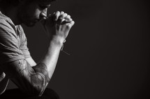 a man with a sleeve tattoo and praying hands.