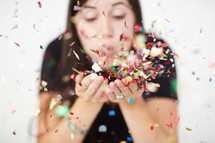 a woman blowing colorful confetti 