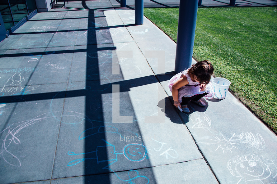 a child drawing with sidewalk chalk 