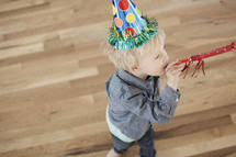 A toddler boy wearing a party hat. 