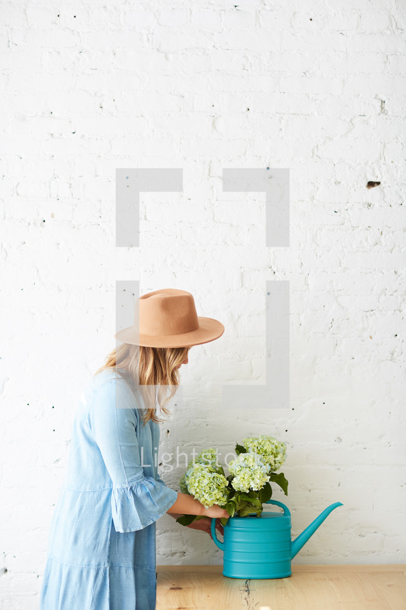 woman arranging a watering can with hydrangeas 