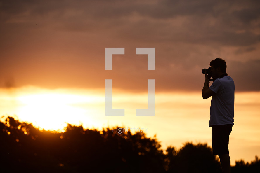 a man taking pictures at sunset 