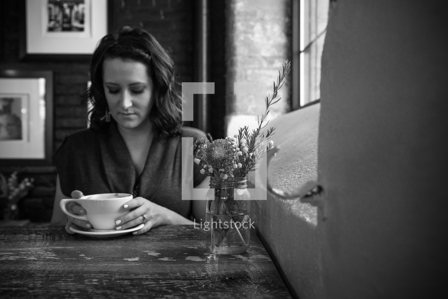 a woman sitting at a window seat in a coffee shop 