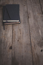 A Bible, notebook and pen on a wooden table