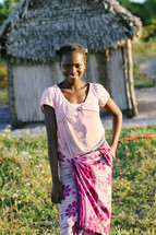 young girl posing in front of a hut 