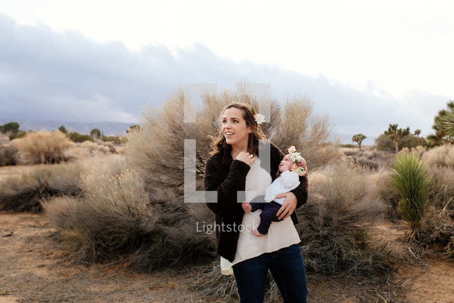 A mother holding a baby girl in the desert 