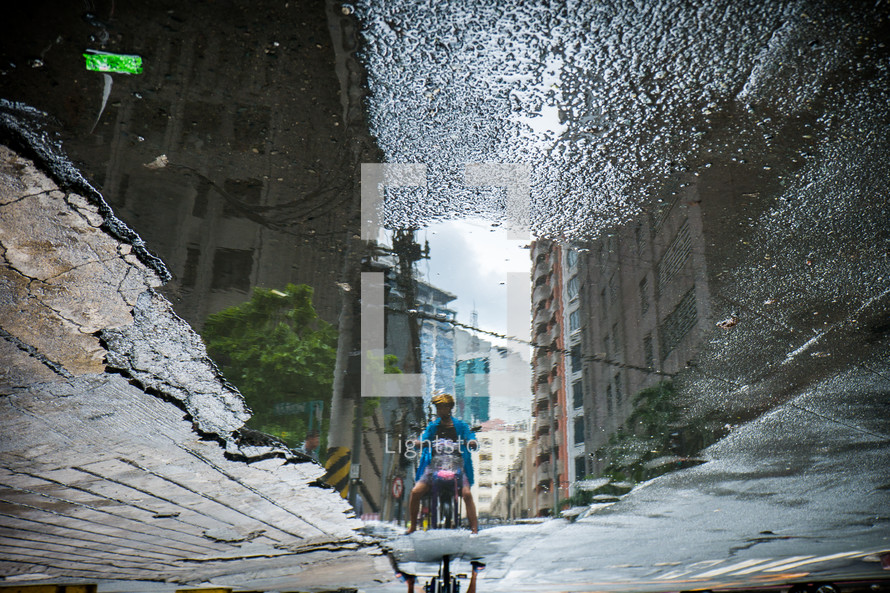 reflection in a puddle of a man on a motorcycle 