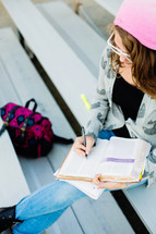 Teenage girl back to school studying, ready bible, campus, on bleachers,  devotional
