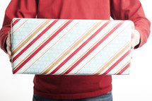 A man holding out gift wrapped in striped wrapping paper