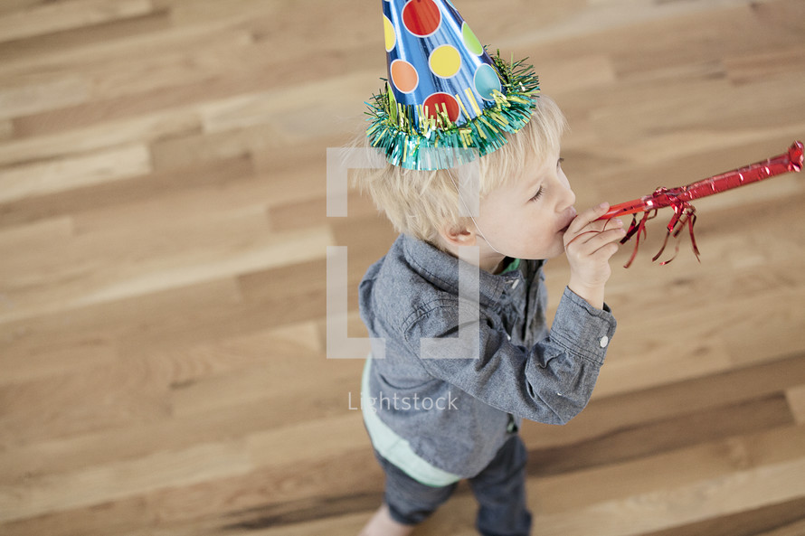 A toddler boy wearing a party hat. 