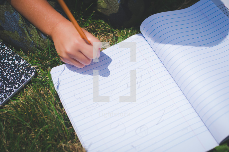 boy writing in a notebook on the grass
