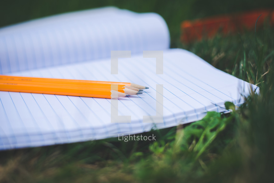 pencils on a notebook on the grass