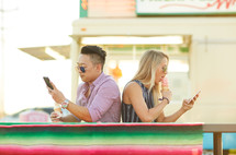 man and woman ignoring each other eating ice cream and texting 