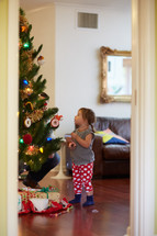 a little girl decorating a Christmas tree