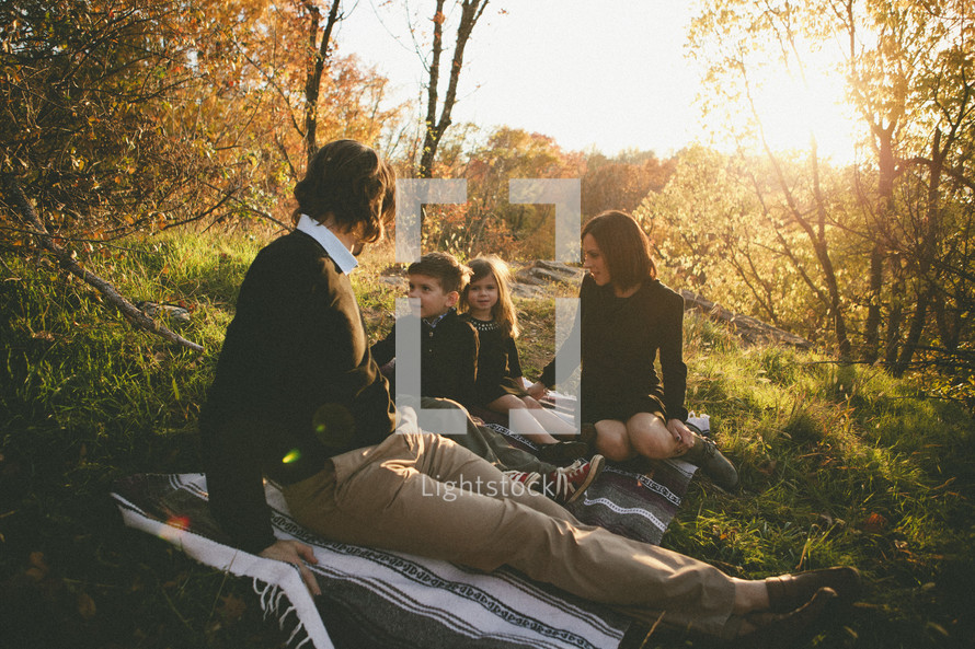 family sitting on a blanket in the woods