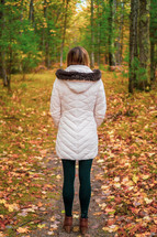 a woman walking on a path in a forest in fall 