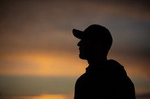 silhouette of a man in a ball cap at sunset 