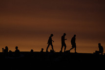 silhouettes of people taking pictures of the sunset on a beach 