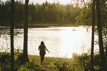 a woman walking by the edge of a lake 
