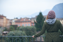 woman standing at a railing looking out at a town 