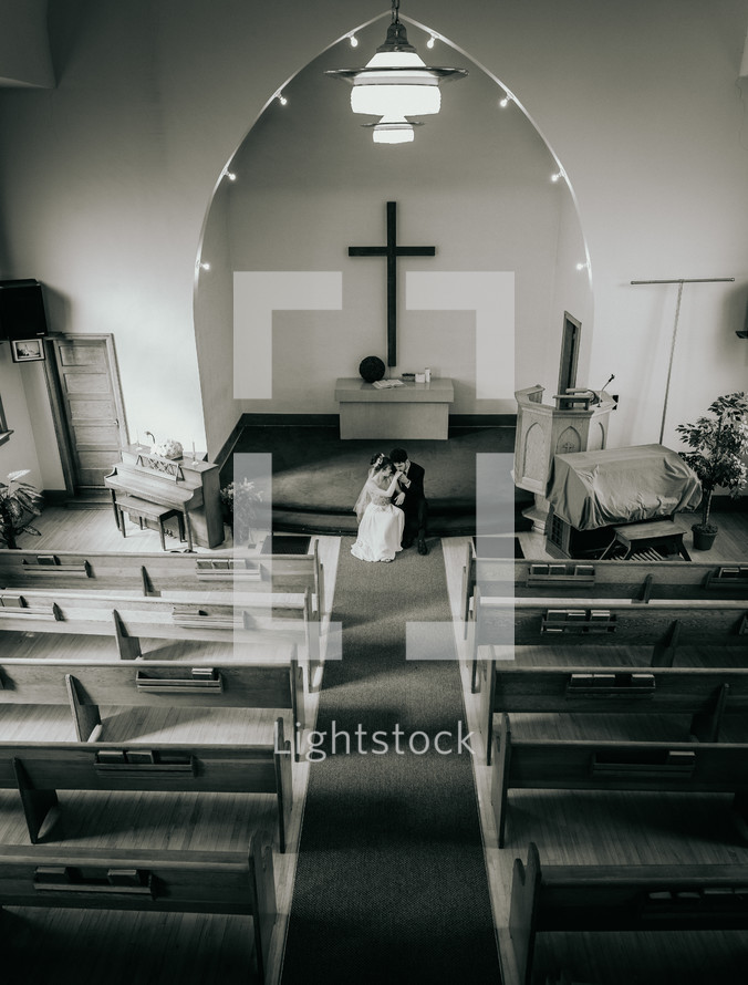 Black and white photo of a bride and groom in a chapel on their wedding day.