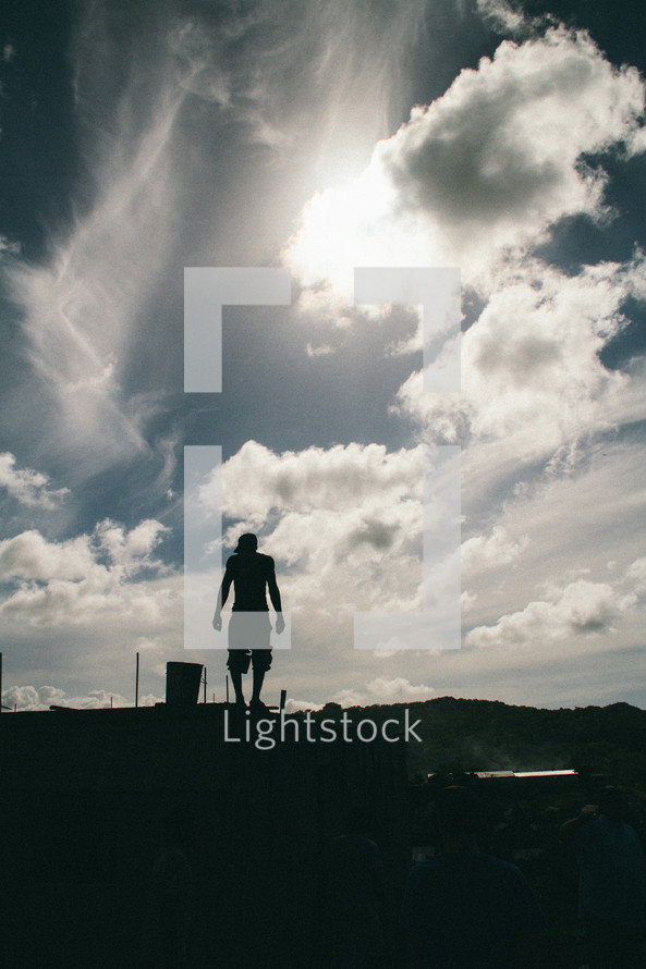 silhouette of a man standing under a cloudy sky 