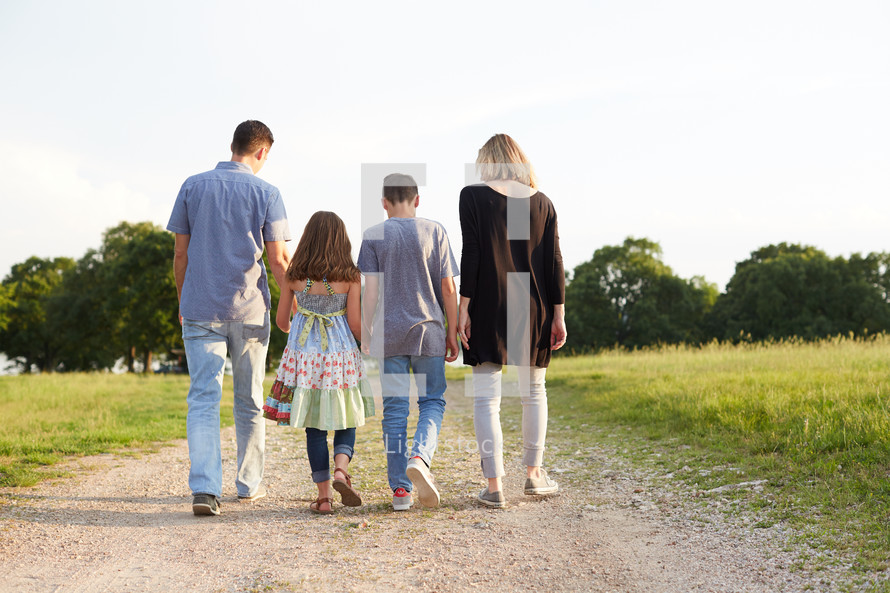 a family walking together with arms around each other down a rural road 
