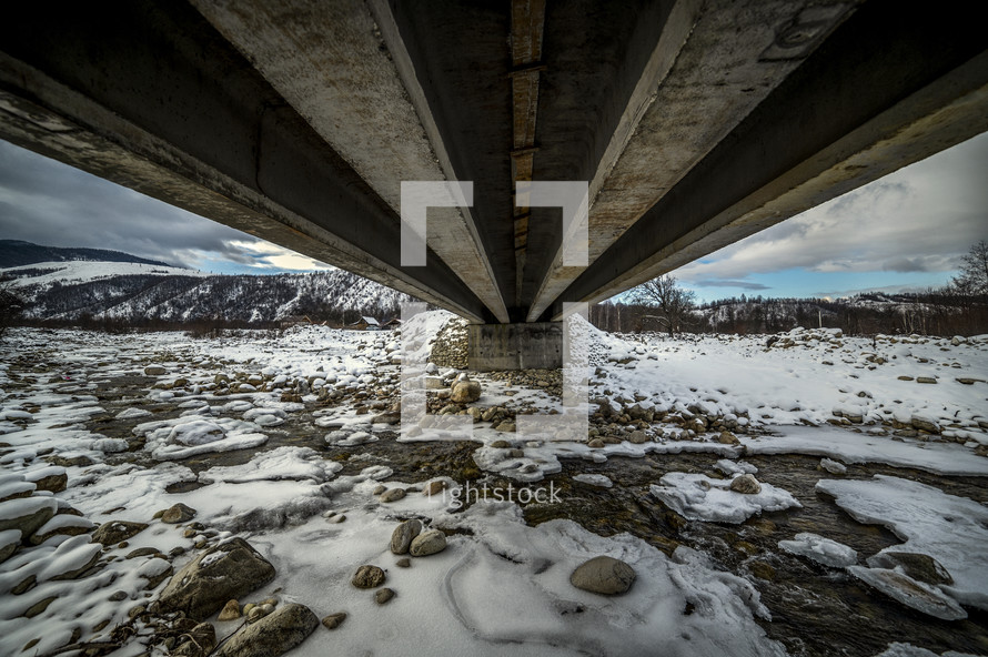 snow on a river under a bridge 