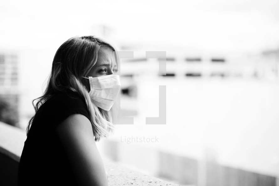 a young woman with a mask looking over a railing 