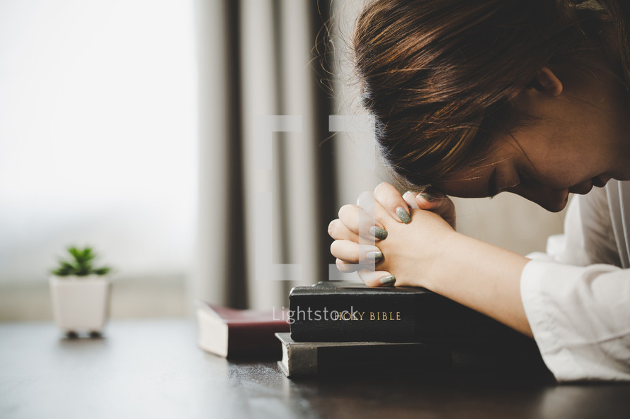 Asian woman praying with her Bible
