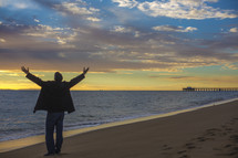 man with raised hands on a beach