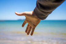 reaching hand towards the ocean 