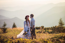 Bride and groom standing in front of a a mountain landscape 