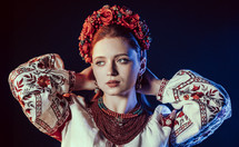 Charming ginger woman in traditional ukrainian handkerchief, necklace and embroidered blouse at black background. Ukraine, style, folk, ethnic culture. High quality photo