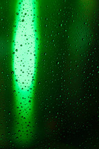 green bokeh light and rain drops on a window 