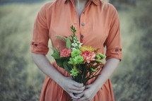 a woman in a dress holding a bouquet of flowers 